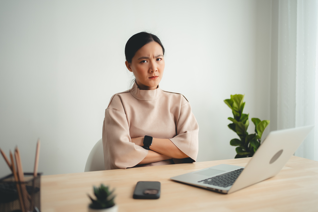 Asian Woman Using Laptop Suffering From Problem With Work Or Financial, Looking To Camera.